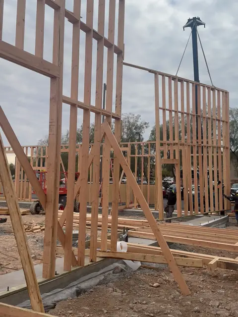 Crew guiding a crane-set wood wall panel onto the stem-wall foundation at The Industry Studios, Henderson NV, January 2026